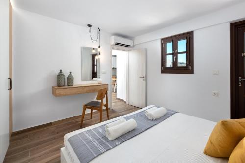 a white bedroom with a bed and a chair at Lindos Heart Apartments in Líndos