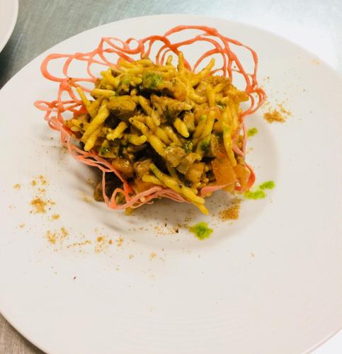 a white plate with a pasta dish on it at Hotel Villaggio Ristorante Pizzeria Museo TANIT in Carbonia