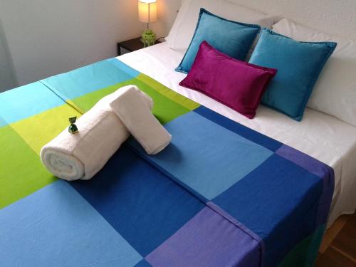un letto con coperta colorata e cuscini sopra di Roble a Madrid