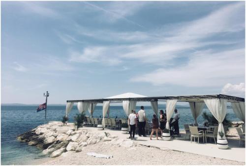 a group of people standing under a tent on the beach at Apartments Maja in Podstrana
