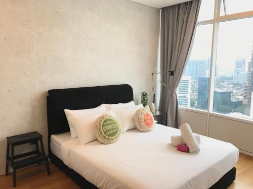 a bedroom with a bed with white pillows and a window at VORTEX SUITES KLCC by PNUT With NETFLIX in Kuala Lumpur