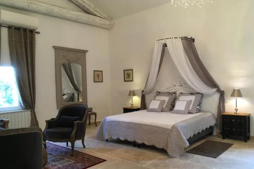 ein Schlafzimmer mit einem weißen Bett mit Himmelbett in der Unterkunft Château de la Merletade in Cheval-Blanc