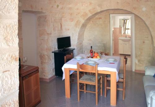 ein Esszimmer mit einem Tisch und einem TV in der Unterkunft Il Trullo di Nonna Enza in Castellana Grotte