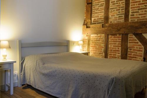 a bedroom with a bed and a brick wall at Hôtel Les Chevaliers in Laon
