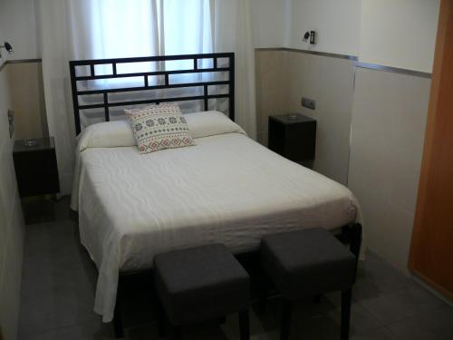 a small bedroom with a bed with two stools at Hostal la Hispanidad in Málaga