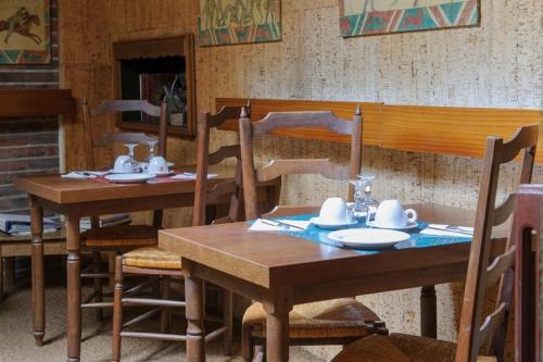 two wooden tables and chairs with plates and cups on them at Hôtel Les Chevaliers in Laon