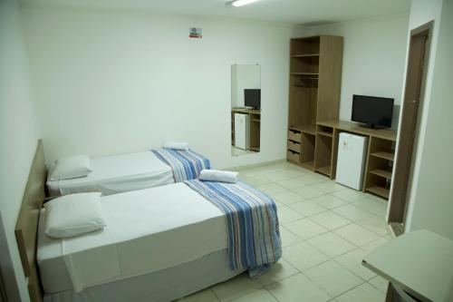 a bedroom with two white beds and a television at Hotel Macapaba in Macapá