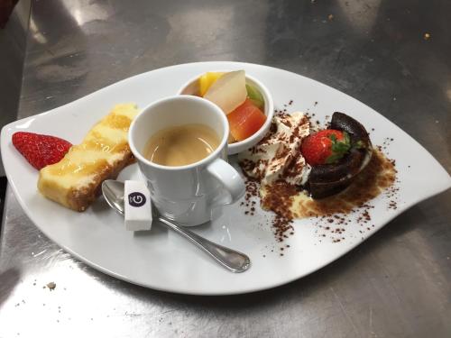 a plate of food with a cup of coffee and fruit at Villa Motel in Stenay