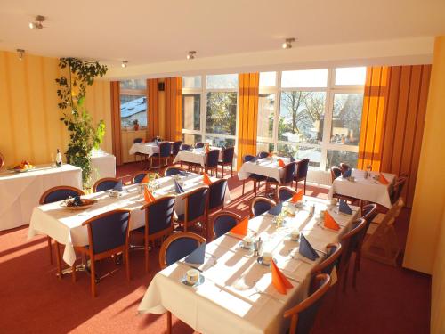 a restaurant with white tables and chairs and windows at Altes Doktorhaus - Hotel Garni in Willingen