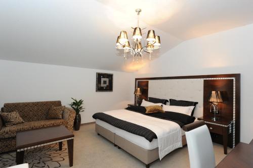 a bedroom with a bed and a chair and a chandelier at Guesthouse Dolinsek in Sevnica