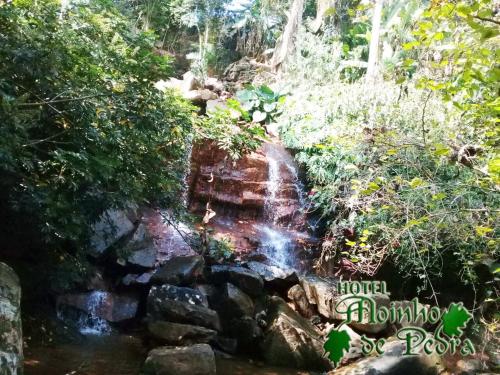 a waterfall in the middle of a forest at Hotel Moinho de Pedra in Serra Negra