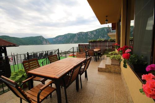 a table and chairs on a balcony overlooking a lake at Vila Golful Dunării in Dubova