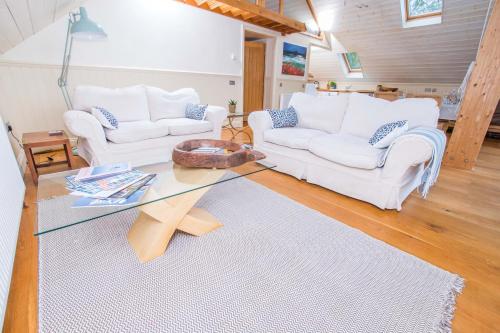 uma sala de estar com dois sofás brancos e uma mesa de vidro em The Garden Studios em Budleigh Salterton