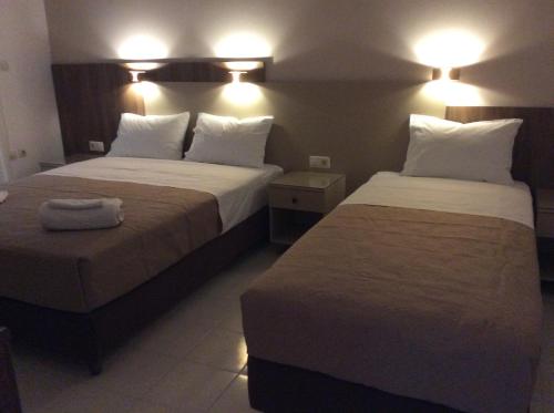 two beds in a hotel room with lights on at Erato Apartments in Petalidhion
