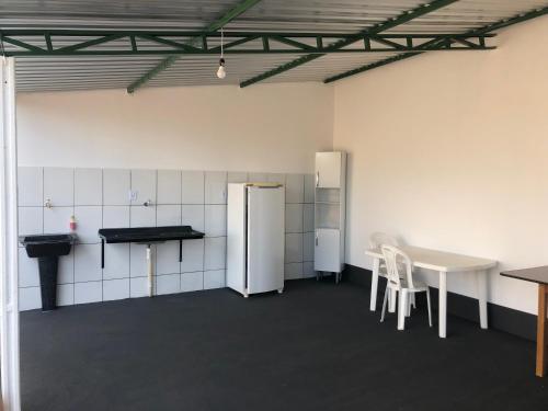 Nova América da ColinaにあるPousada LMの冷蔵庫、テーブル、椅子が備わる客室です。