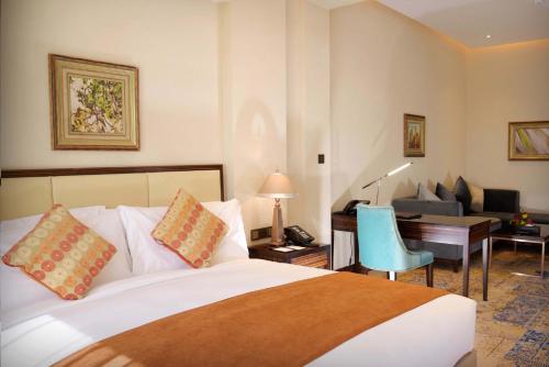a hotel room with a bed and a desk and a chair at Warwick Al Khobar in Al Khobar