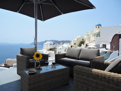 a patio with chairs and a table with an umbrella at Aqua & Terra Traditional Cave Houses in Oia