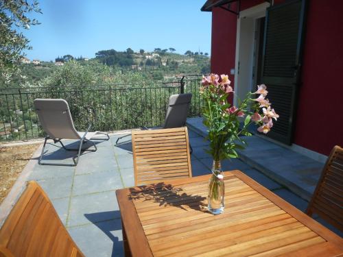 a vase of flowers on a wooden table with chairs at A Baracca du Pei in Imperia