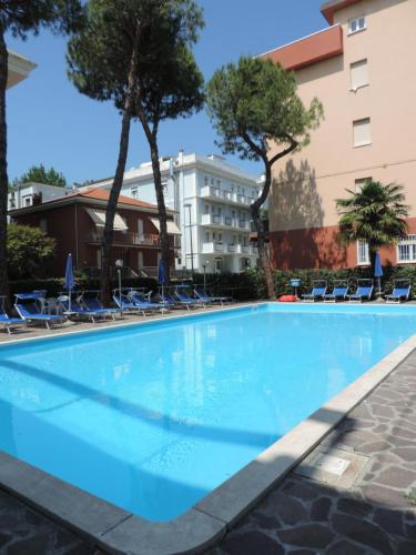 a large swimming pool with chairs and a building at Hotel Liliana in Rimini