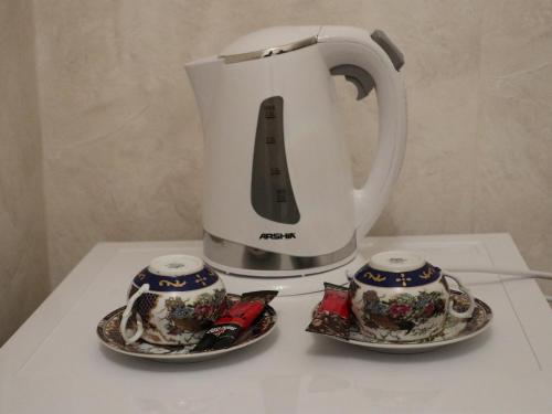 a coffee pot and two tea cups on a table at Liberty Apartment And Rooms in Tbilisi City