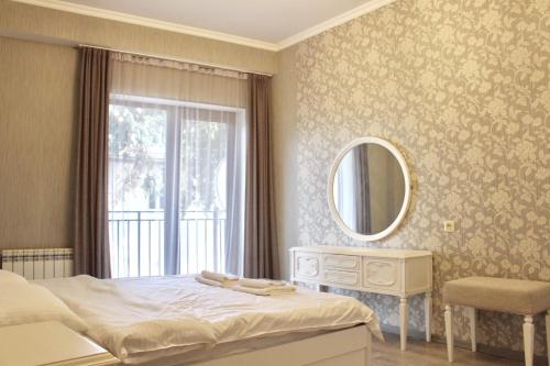 een slaapkamer met een bed, een spiegel en een raam bij Genacvale in Tbilisi City