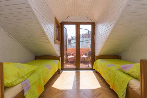 a attic bedroom with two beds and a balcony at Apartment Neva with Terrace in Baška