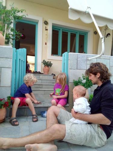 a man holding a baby and two children sitting on a bench at Mochlos Beach Villa Seafront house in Mochlos