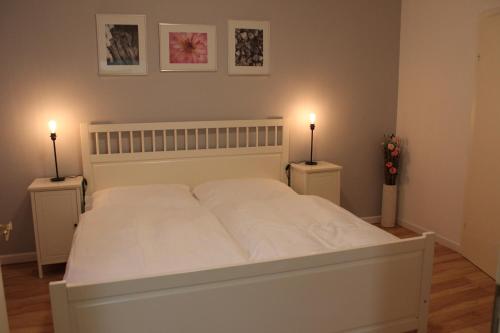 a bedroom with a white bed with two lights on it at City Apartment Schladming in Schladming