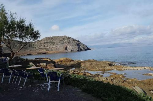 a group of chairs and tables next to the ocean at Mochlos Beach Villa Seafront house in Mochlos