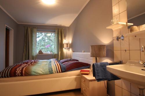 a bedroom with a bed and a sink and a window at Armarova Ihre Ferienpension in Cuxhaven