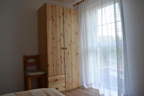 ein Schlafzimmer mit einem Holzschrank und einem Fenster in der Unterkunft Velická izba in Poprad