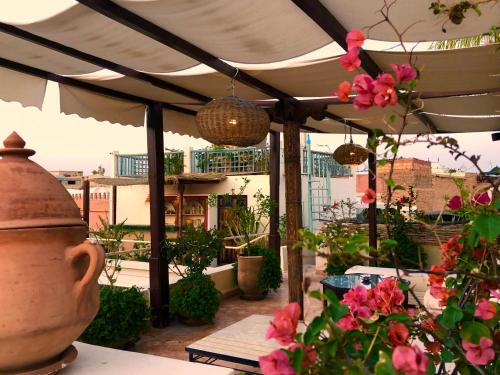 an outdoor patio with pink flowers and a vase at Riad Le Coq Berbère in Marrakech