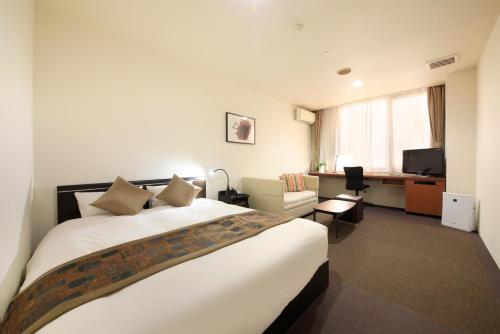 a hotel room with a large bed and a desk at Hotel Tohkai in Atsugi