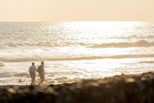 two people standing on a beach looking at the ocean at Hotel Terraza del Pacifico in Jacó