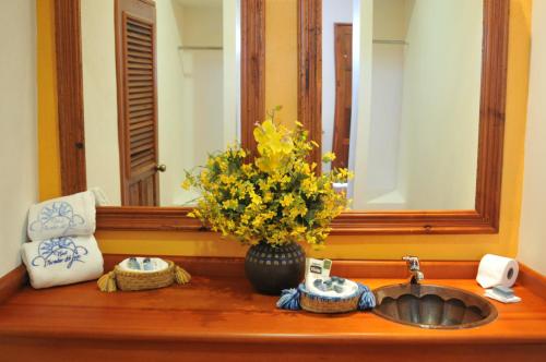 a bathroom sink with a vase of flowers and a mirror at Mirador del Lago in Pátzcuaro