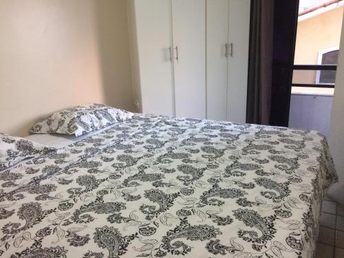 a bed with a black and white blanket on it at Beira Mar da Pajuçara in Maceió