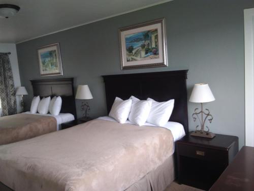 Una habitación de hotel con dos camas y dos lámparas. en Bay Bridge Motel, en North Bend