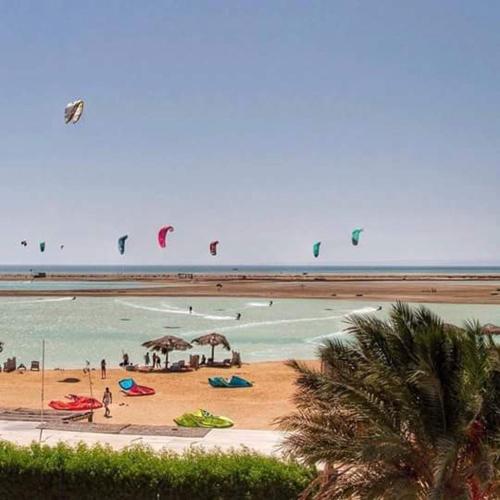 a group of people flying kites on a beach at Green Sudr Resort in Ras Sedr