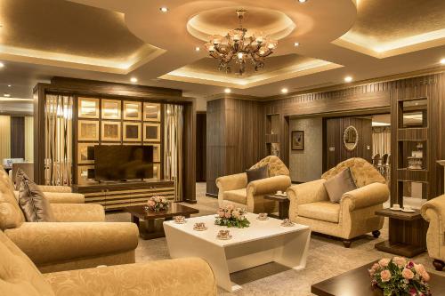 a living room with a couch and chairs and a television at Muong Thanh Luxury Vientiane Hotel in Vientiane