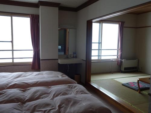 a bedroom with a large bed and a mirror at Highland Lodge Takegen in Myoko