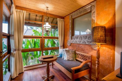 a living room with a bench and a large window at Ulun Ubud Resort - CHSE Certified in Ubud