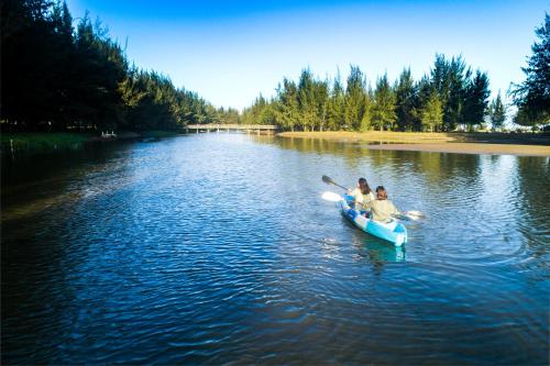 two people in a paddle boat on a river at Seava Ho Tram Beach Resort in Ho Coc