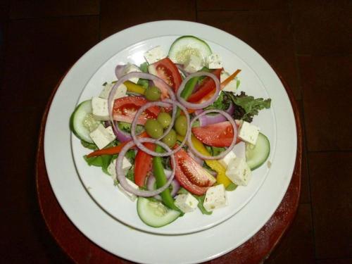 a white plate with a salad with tomatoes and vegetables at Rainbow Village in La Ceiba