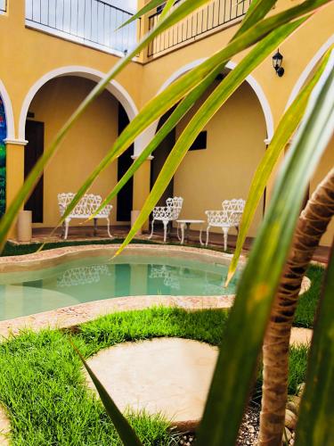 a swimming pool with chairs and a building at Casa Sisal Valladolid Yuc in Valladolid