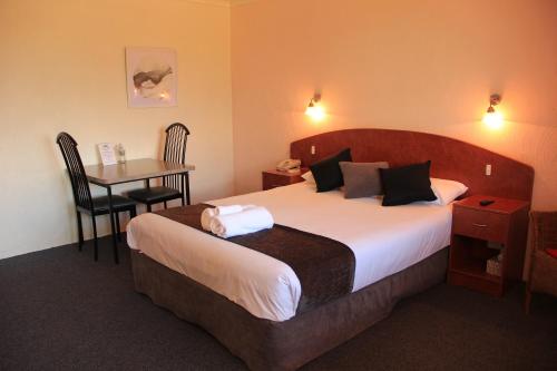 a hotel room with a bed and a table with a desk at Childers Gateway Motor Inn in Childers