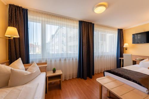 ein Hotelzimmer mit einem Bett, einem Sofa und einem Fenster in der Unterkunft Hotel Royal in München