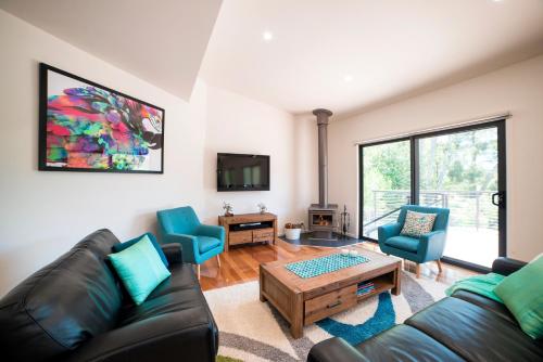 a living room with a couch and chairs and a tv at Golton in the Gap in Halls Gap