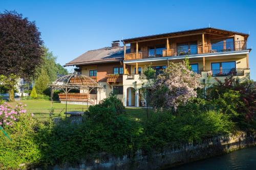 a large house sitting on the side of a river at Garten - Hotel Sallerhof in Salzburg