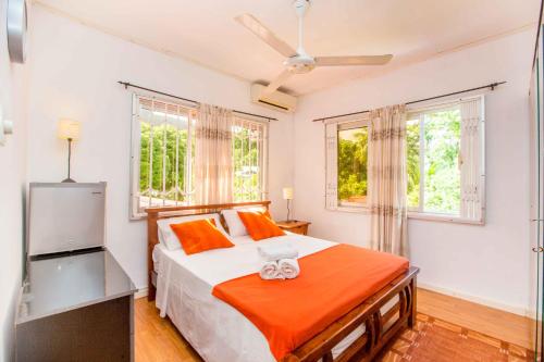 Un dormitorio con una cama y dos ventanas. en The Orchard Holiday Home, en Mahe