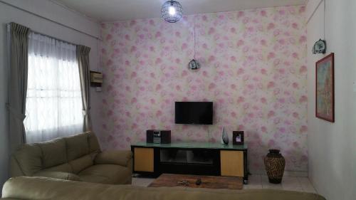 sala de estar con sofá y TV en GuestHouse Taman Megah, Lot 19, en Sandakan